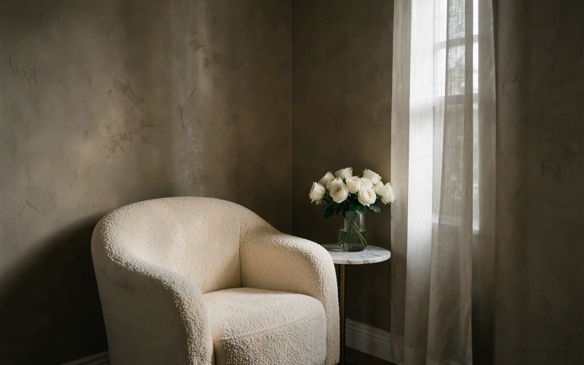 A dim bridal dressing room: an ivory armchair beside a sheer-curtained window and white roses on a marble table (illustrative, generated).