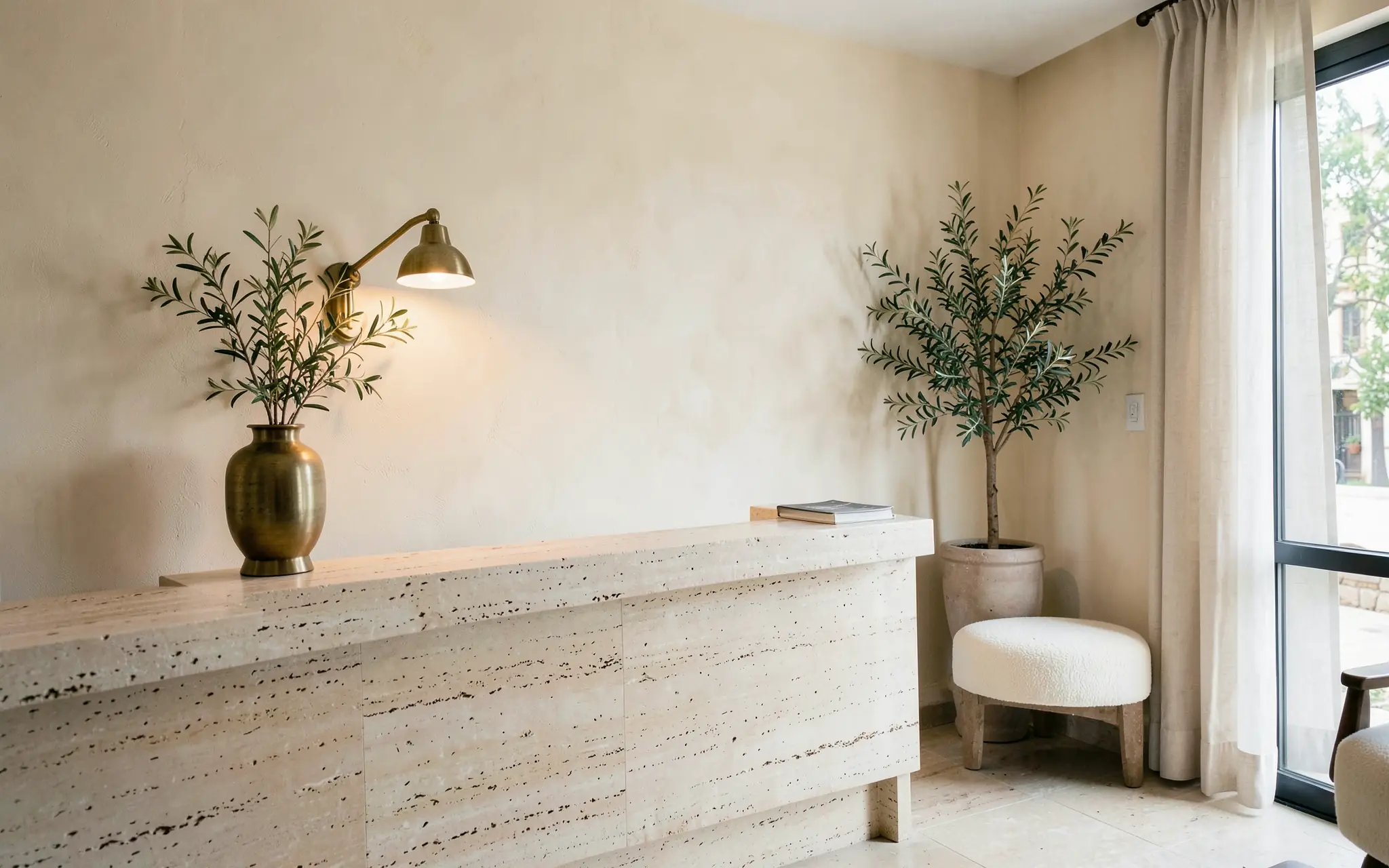 A bright salon reception with a travertine desk, a brass lamp and olive branches (illustrative, generated).